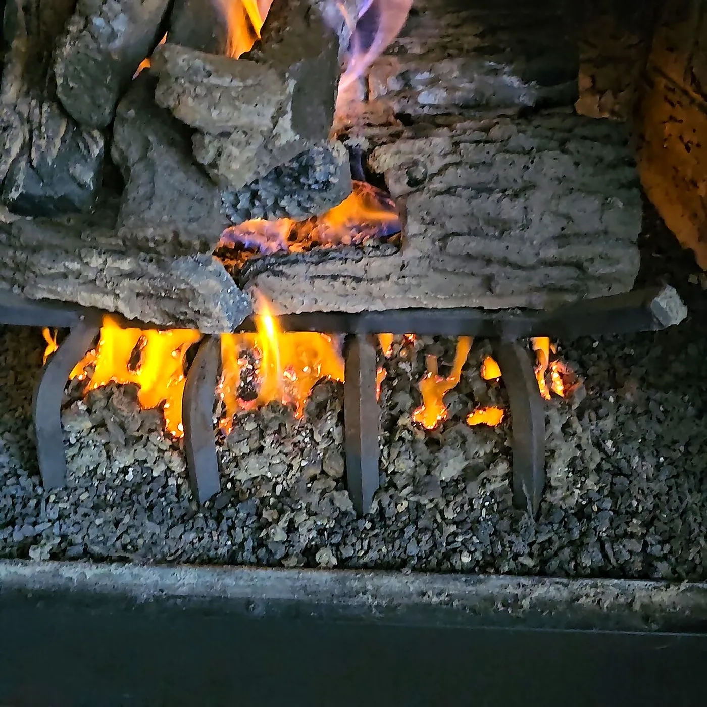 Gas logs burning with a healthy orange flame pattern during a post-service test