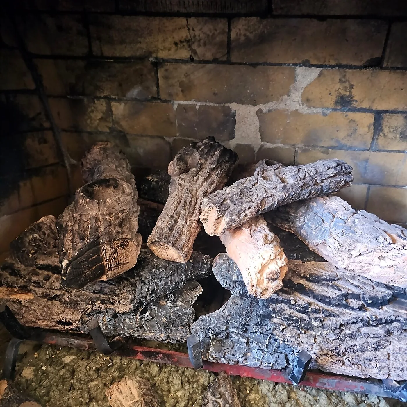 Close view of ceramic gas logs on a burner grate inside a masonry firebox